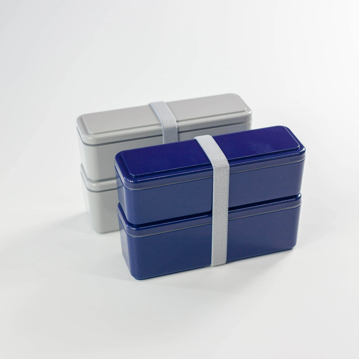 Gel-Cool Square Slim Bento Box 700ml in navy blue and grey, both closed with elastic band, shown side by side from the front on white background