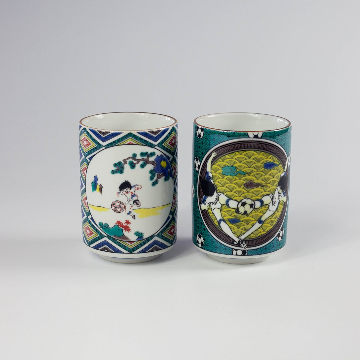 Two ceramic cups with soccer cartoon designs on a gray background