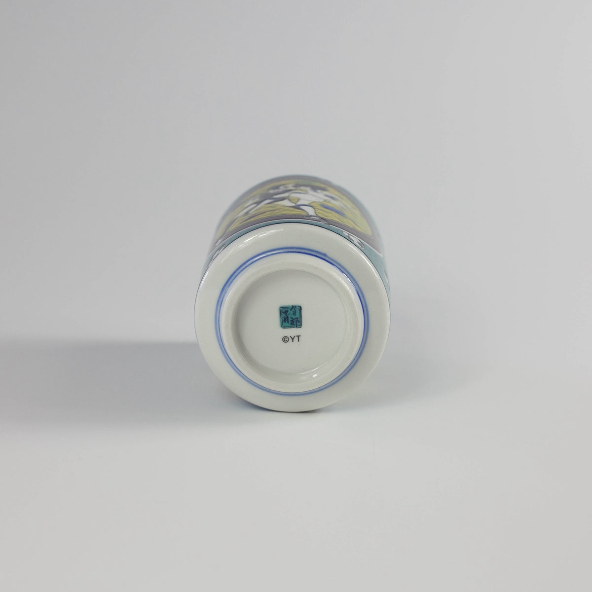 Ceramic tea cup with 'YT' branding on a gray background