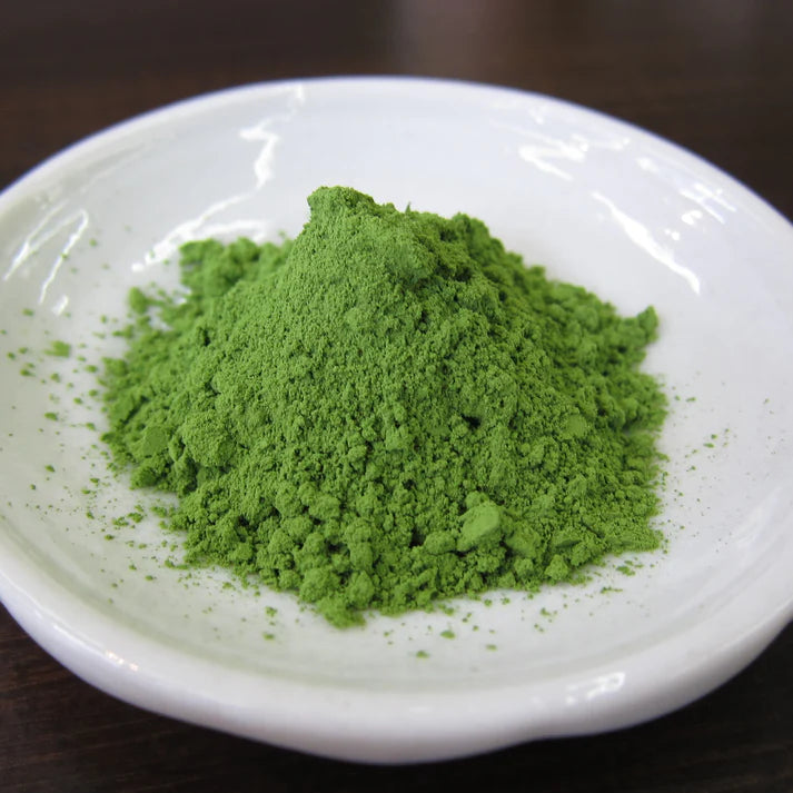 Close-up of vivid green Chikiriya Uji Matcha Green Tea Powder piled on a small white ceramic dish on a dark wooden surface