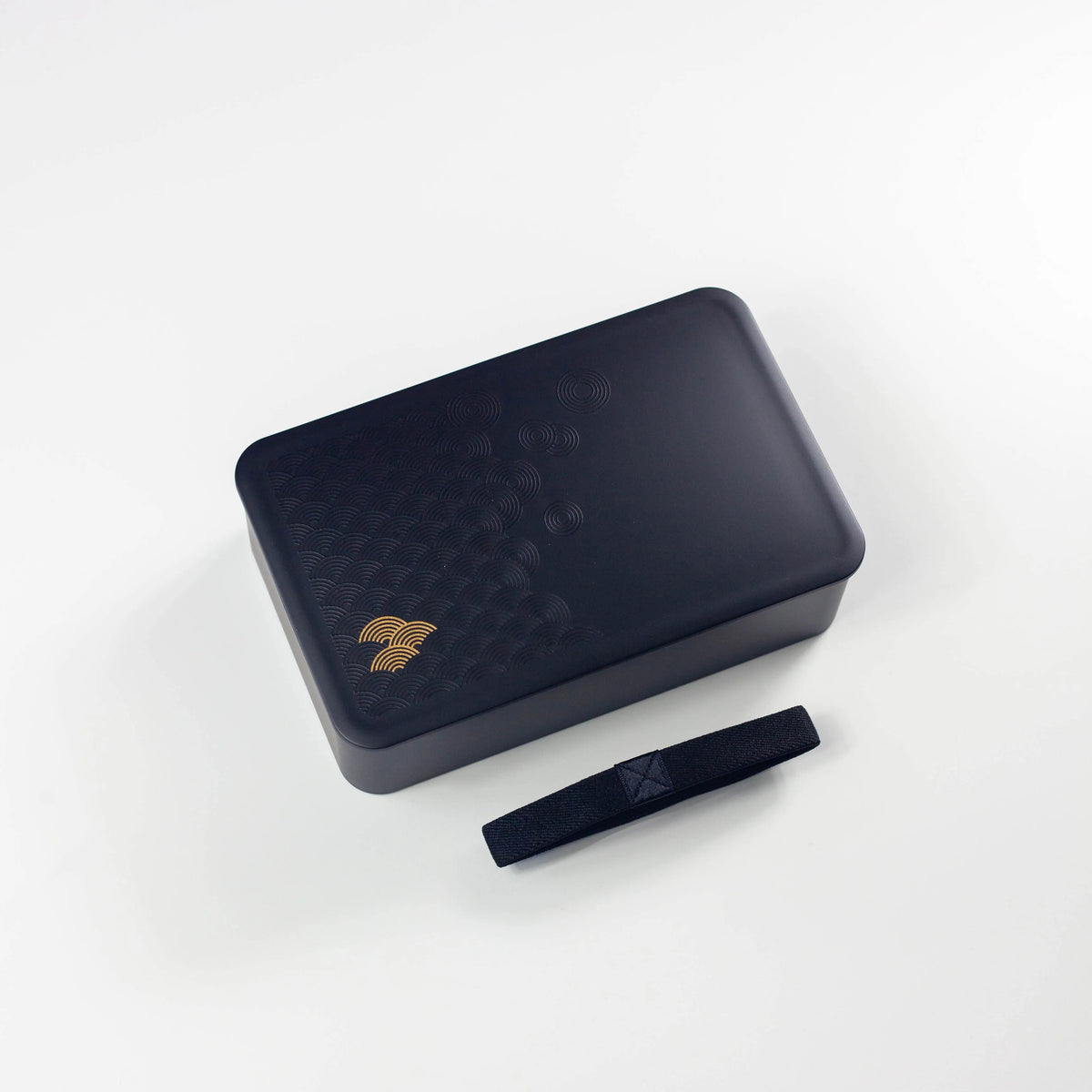 Wamon Bento Box 800mL black – gold seigaiha wave motif on lid, closed with black elastic band, angled view