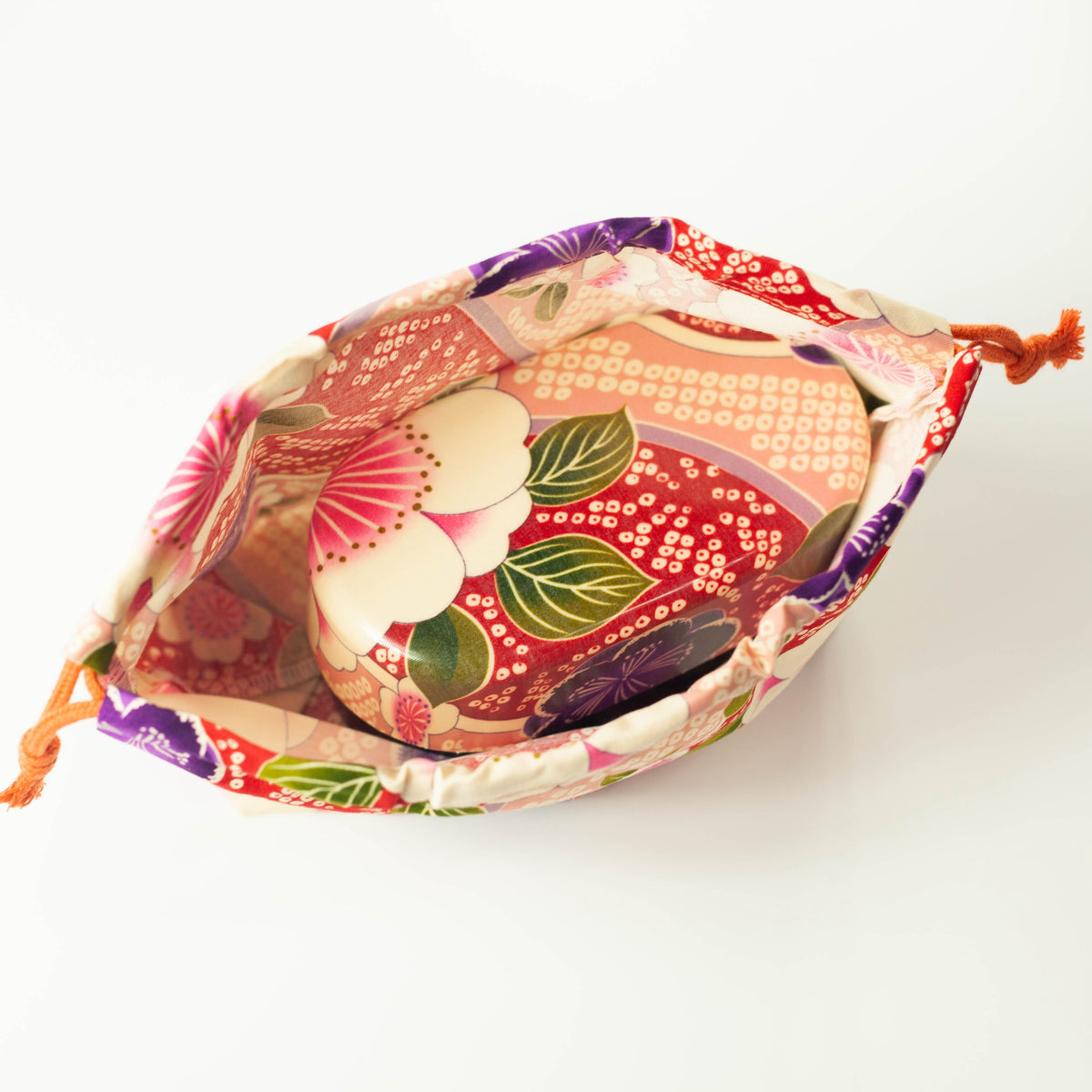 Kimono Sakura Pink bento drawstring bag closed with orange cord tie, pink and red Japanese floral fabric with white sakura, purple and pink flowers, white background