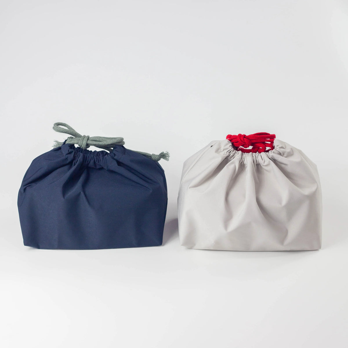 Water Repellent Drawstring Bag in navy blue with grey cord and light grey with red cord, front view on white background