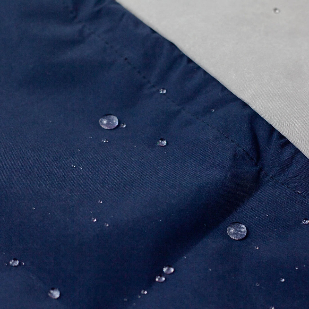 Water Repellent Drawstring Bag laid flat – light grey with red cord (top) and navy blue with grey cord (bottom)