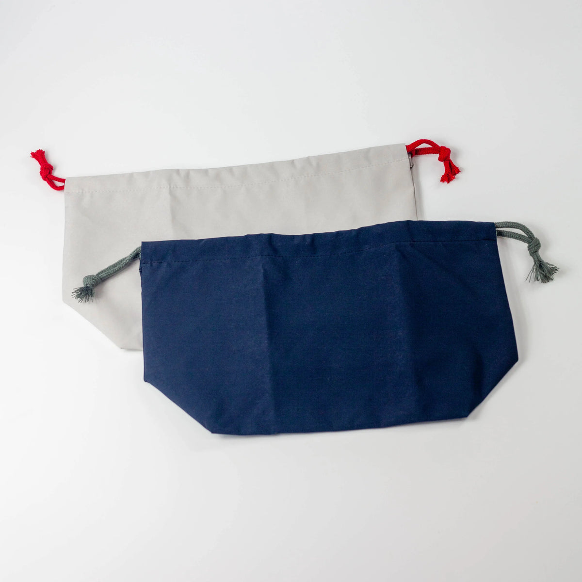 Water Repellent Drawstring Bag in navy blue with grey cord and light grey with red cord, front view on white background