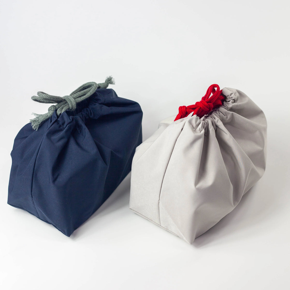 Water Repellent Drawstring Bag in navy blue with grey cord and light grey with red cord, front view on white background
