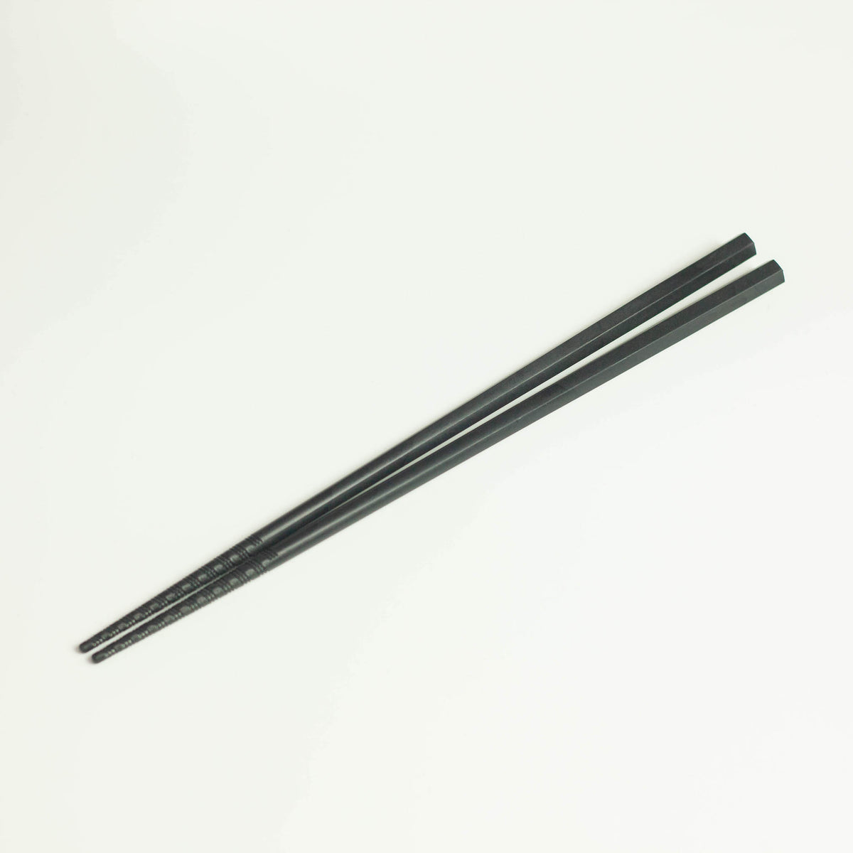 Tornado Chopsticks – pair of matte black resin chopsticks with tornado-grip tips, white background