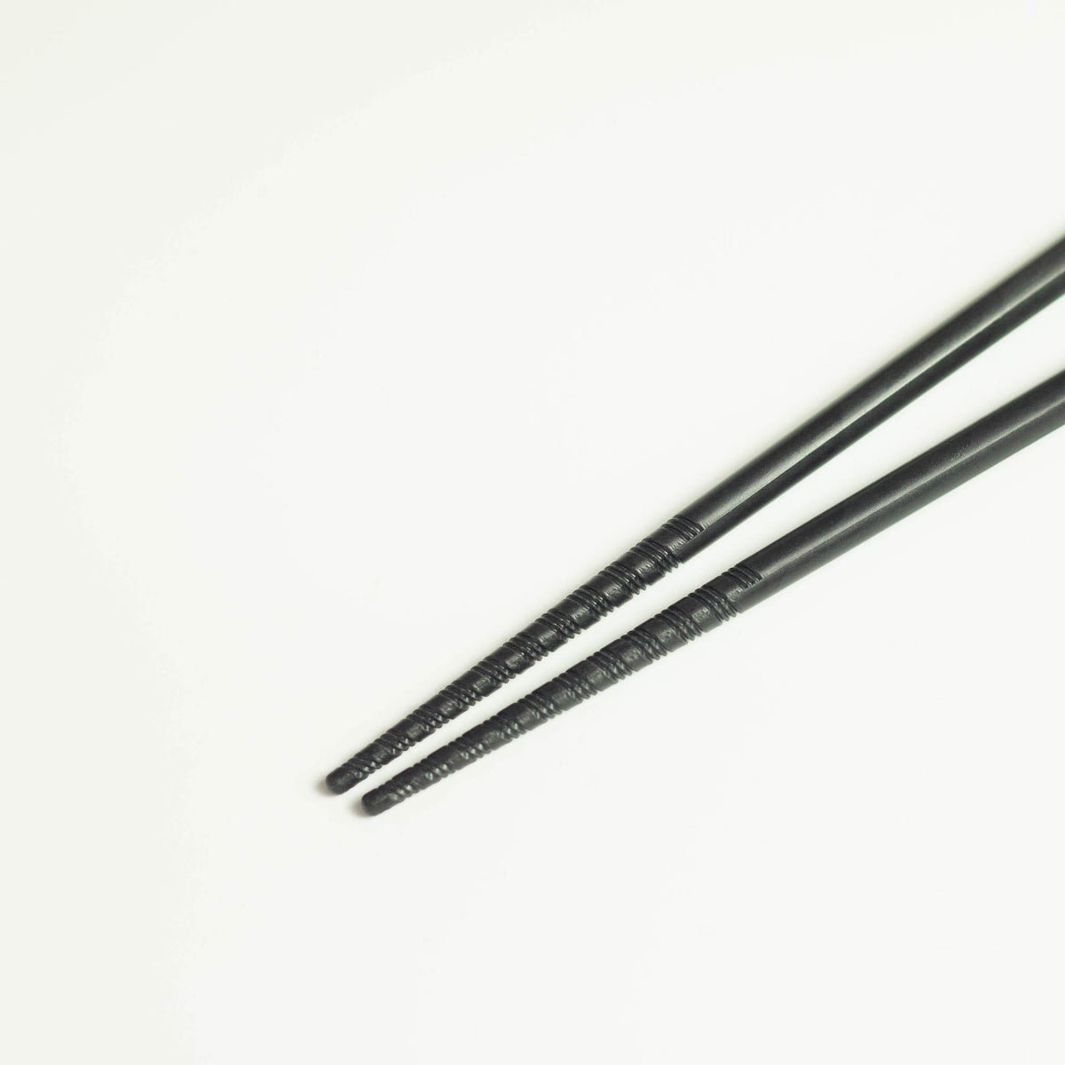 Tornado Chopsticks – pair of matte black resin chopsticks with tornado-grip tips, white background