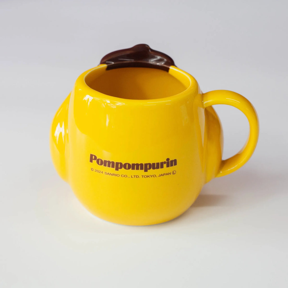 Yellow mug with handle and Sanrio's Pompompurin copyright on a white background