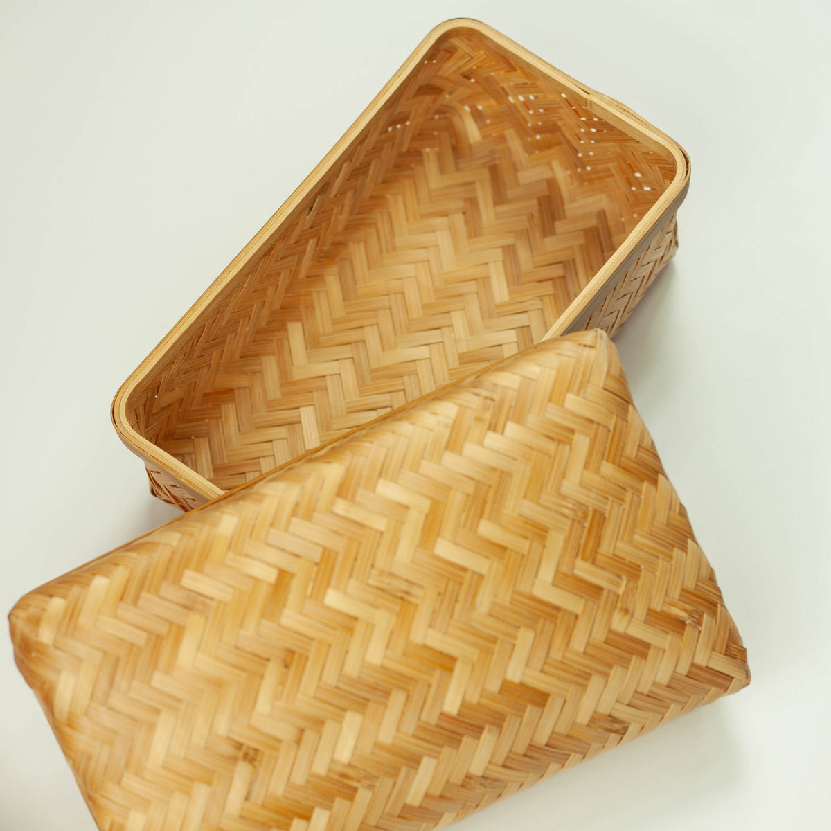 Person holding Woven Bamboo Bento Box with red braided cord on pink background, showing size reference