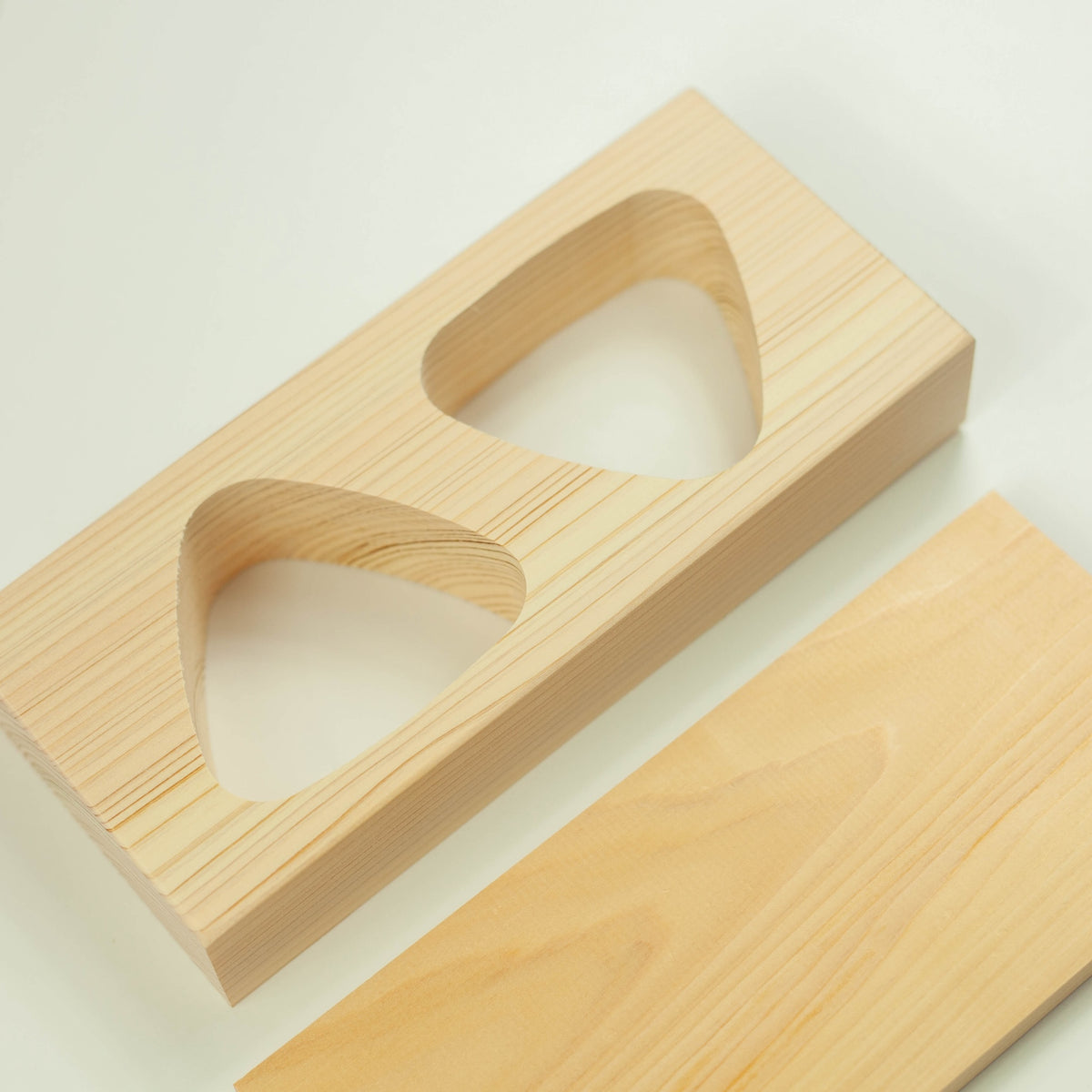 Hinoki Onigiri Mold – Japanese cypress wood rice ball mold with two triangle-shaped cavities for making perfectly shaped onigiri, shown with freshly made rice balls, made in Japan