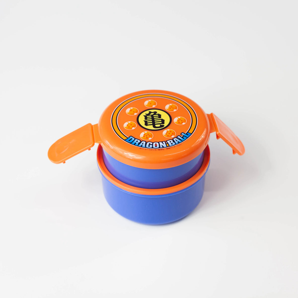 Dragon Ball two-tier round bento box with orange side clips opened and blue containers stacked beneath the lid