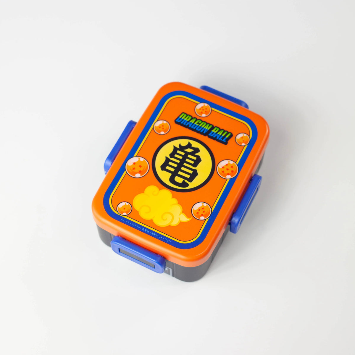 Dragon Ball rectangular bento box with an orange lid, blue clips, and a Kame emblem surrounded by Dragon Balls and Flying Nimbus