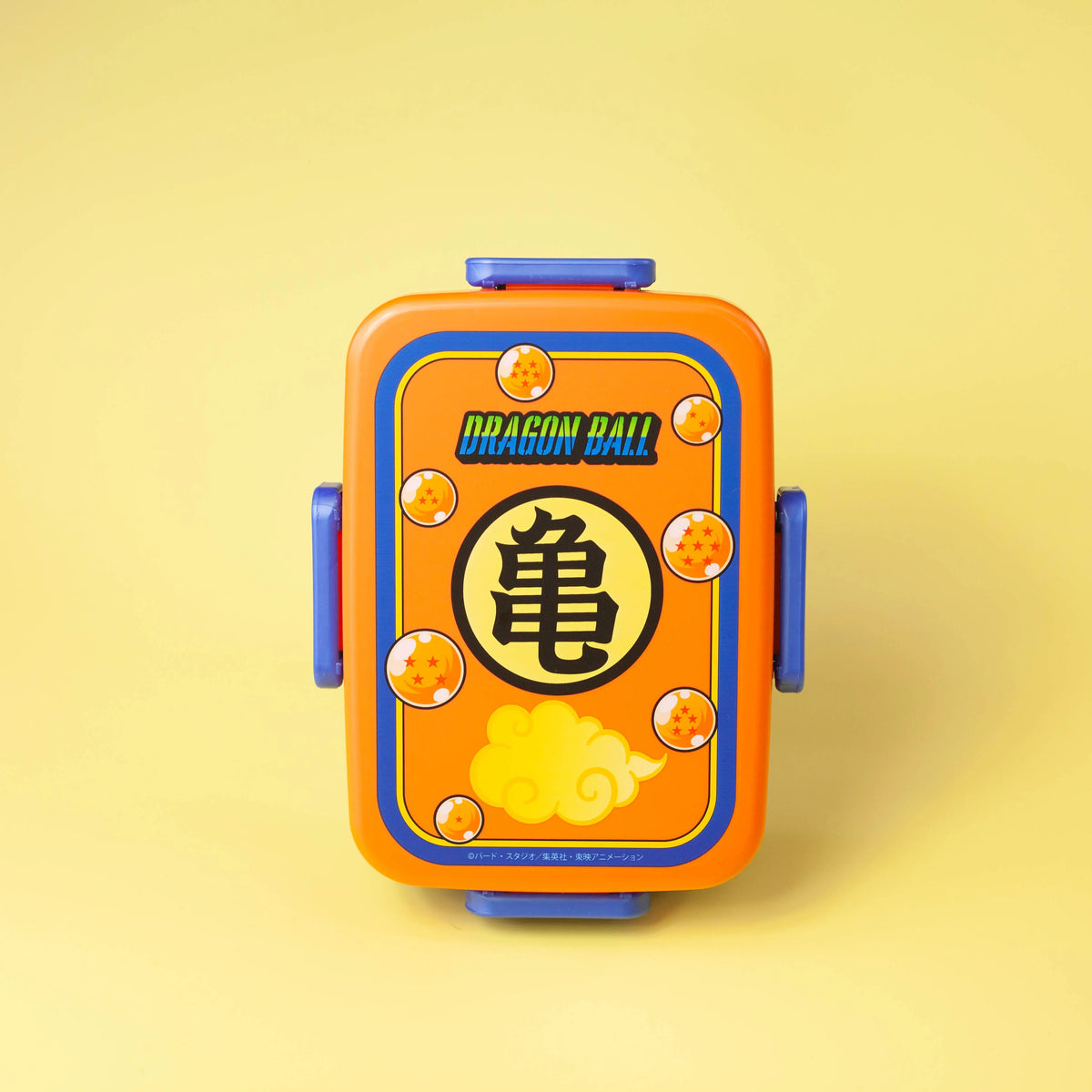 Dragon Ball rectangular bento box displayed upright on a yellow background, showing the Kame emblem, seven Dragon Balls, and Flying Nimbus