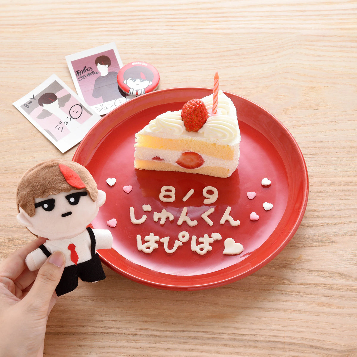 Hiragana Cutter Set used to write a birthday message on a red plate with strawberry shortcake, plush toy, and Polaroid photos