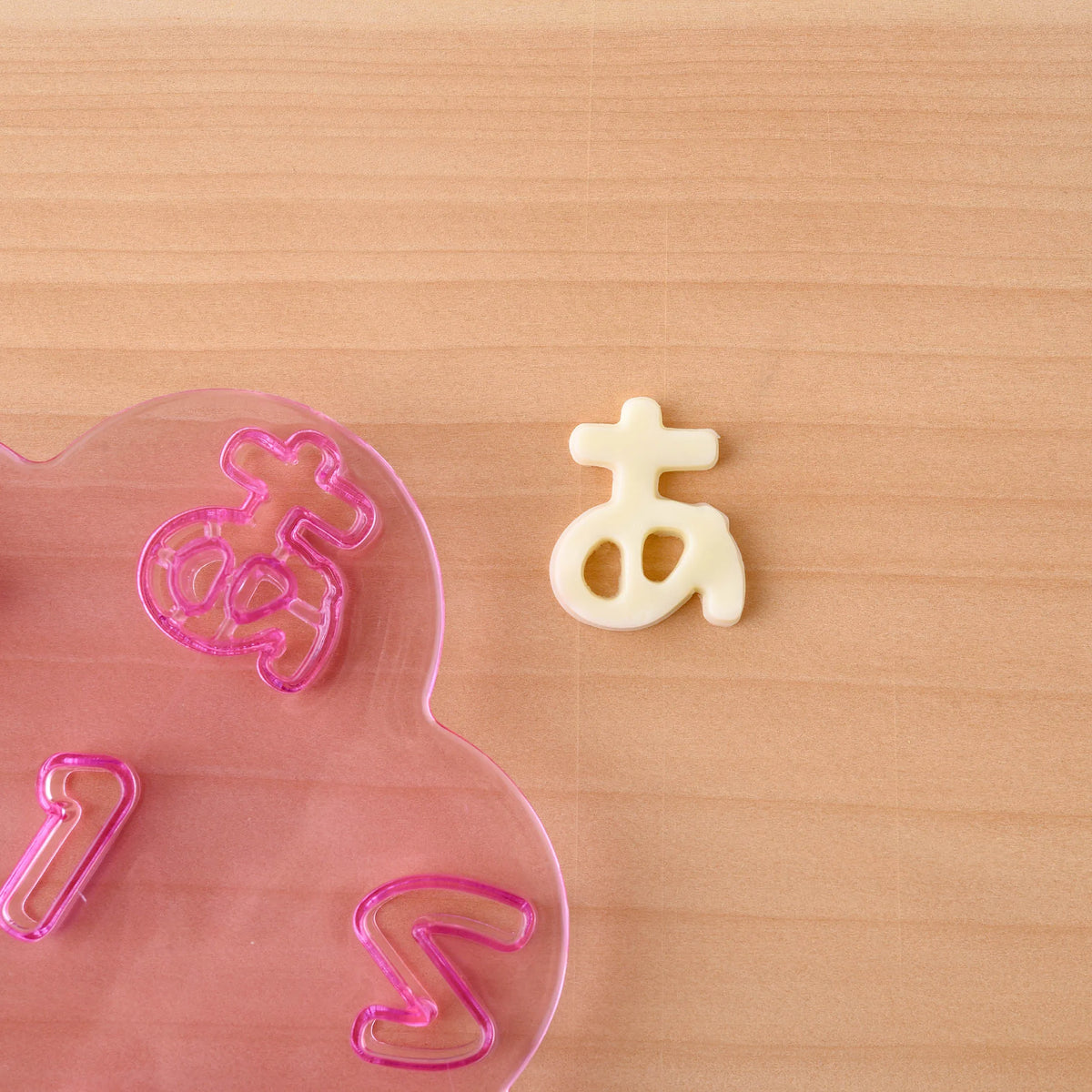 Close-up of Hiragana Cutter Set pink tray – transparent "a" (あ) character cutter showing detailed cutting edge