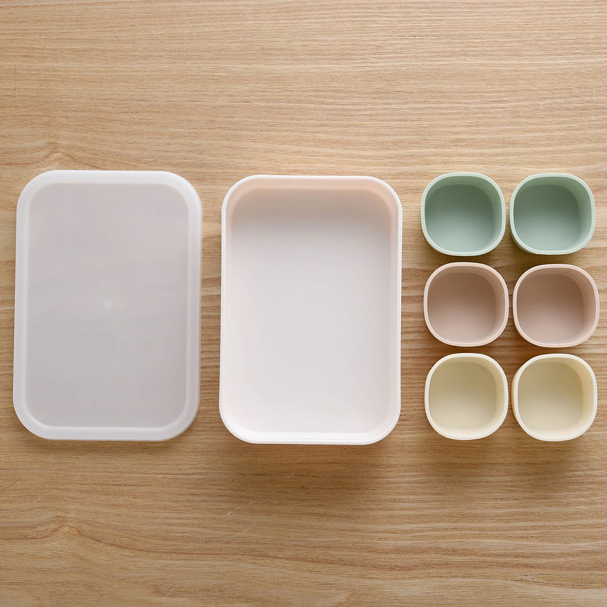Marumi Silicone Cup Set Round – white tray with lid and 6 round silicone cups in mint green, pink, and yellow, top-down view on wooden surface
