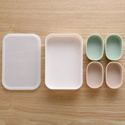 Marumi Silicone Cup Set Rectangle – white tray with lid and 4 oval silicone cups in mint green and pink, top-down view on wooden surface