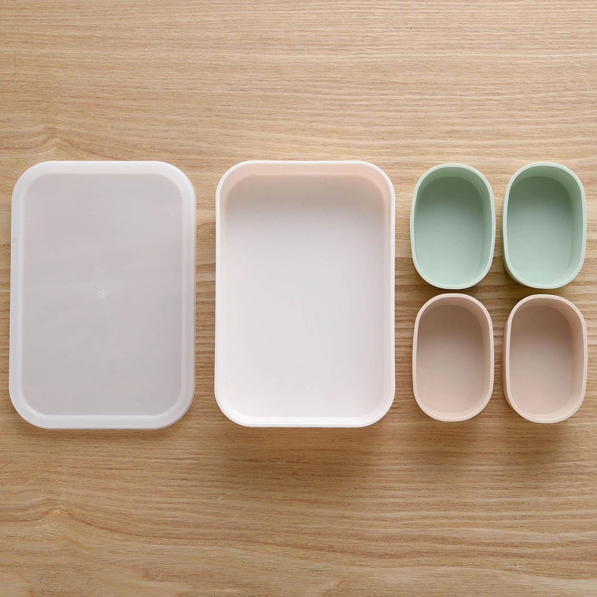 Marumi Silicone Cup Set Rectangle – white tray with lid and 4 oval silicone cups in mint green and pink, top-down view on wooden surface