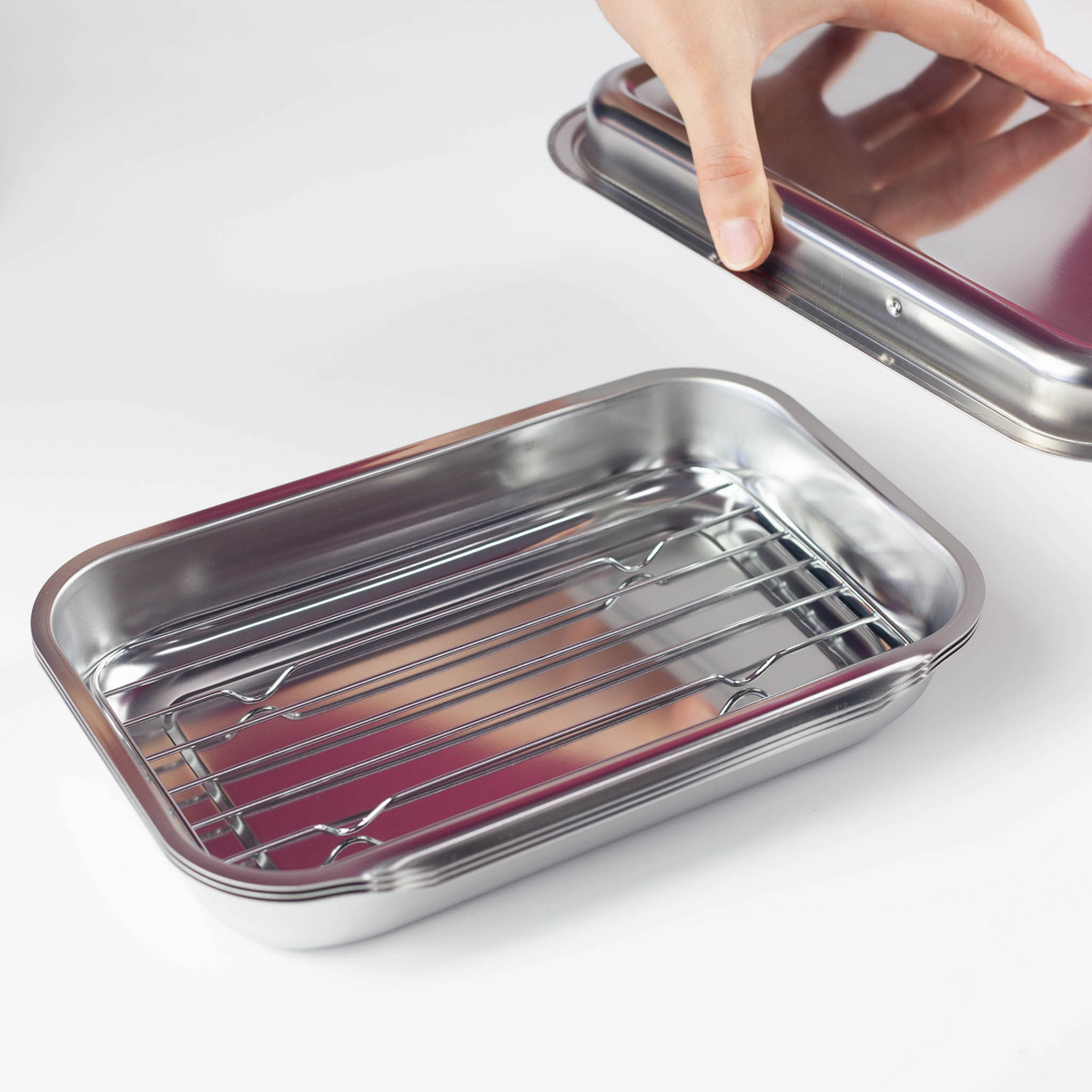 Hand lifting lid of Compact Vat Set revealing polished stainless steel interior tray on white background
