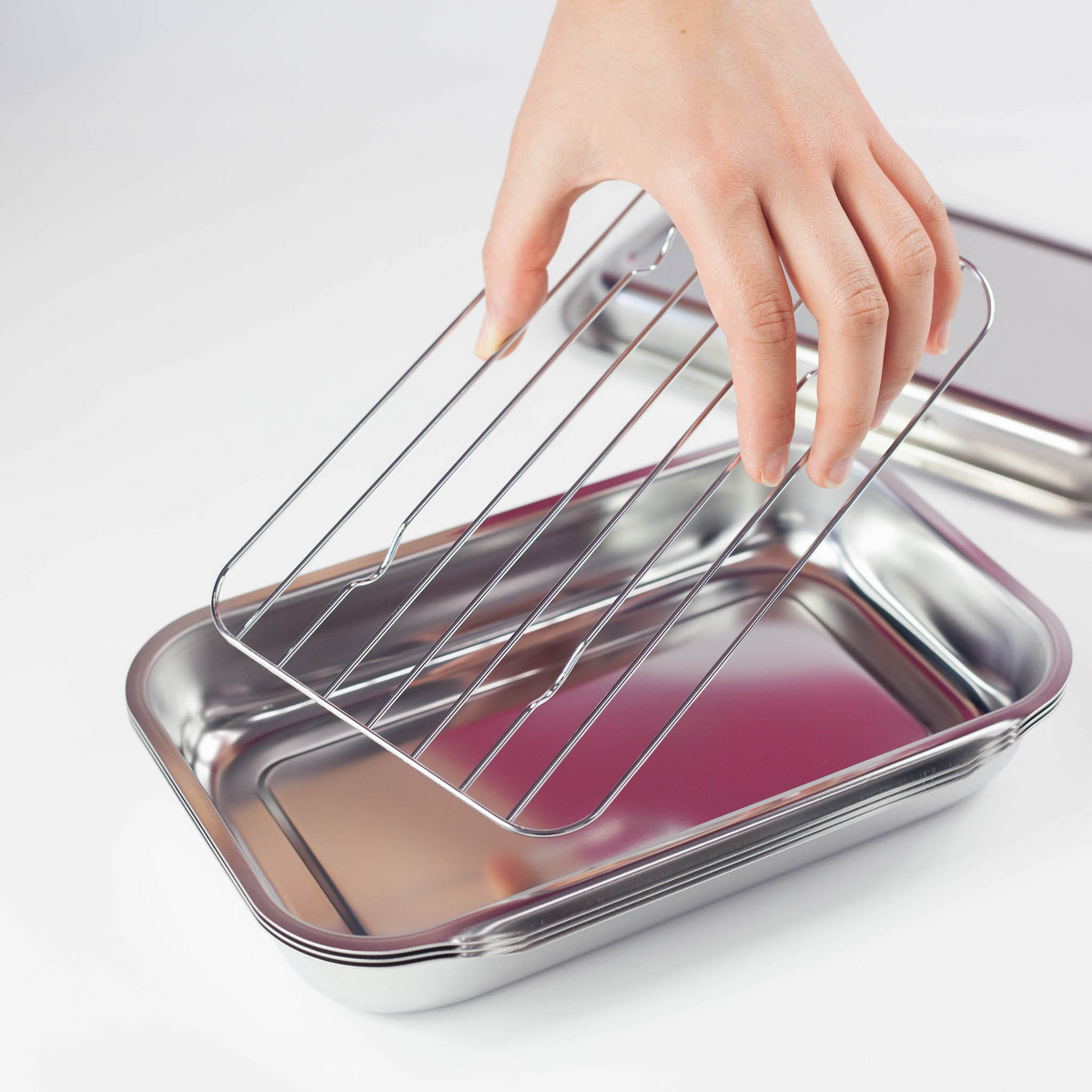 Hand lifting stainless steel wire rack from Compact Vat Set tray, showing rack and tray separated on white background