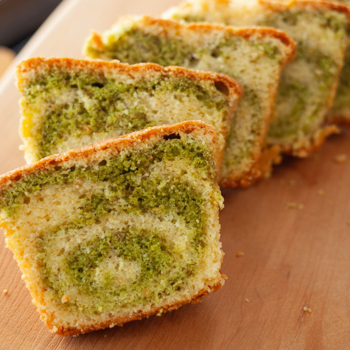 Sliced matcha marble pound cake made with Chikiriya Shizuoka Matcha Powder – golden crust with vivid green swirl pattern, on a wooden cutting board