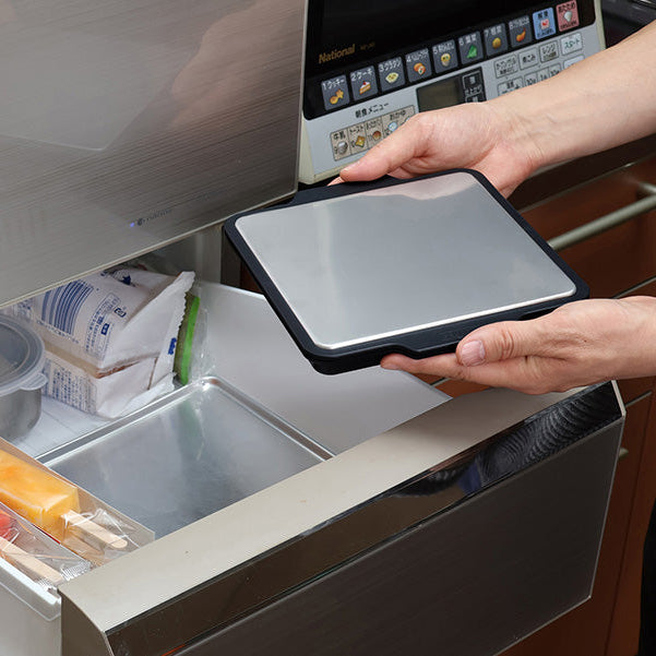 Hands placing the Gel-Cool Rapid Cooling Plate into a freezer drawer beside food items, demonstrating how to pre-freeze the plate before use
