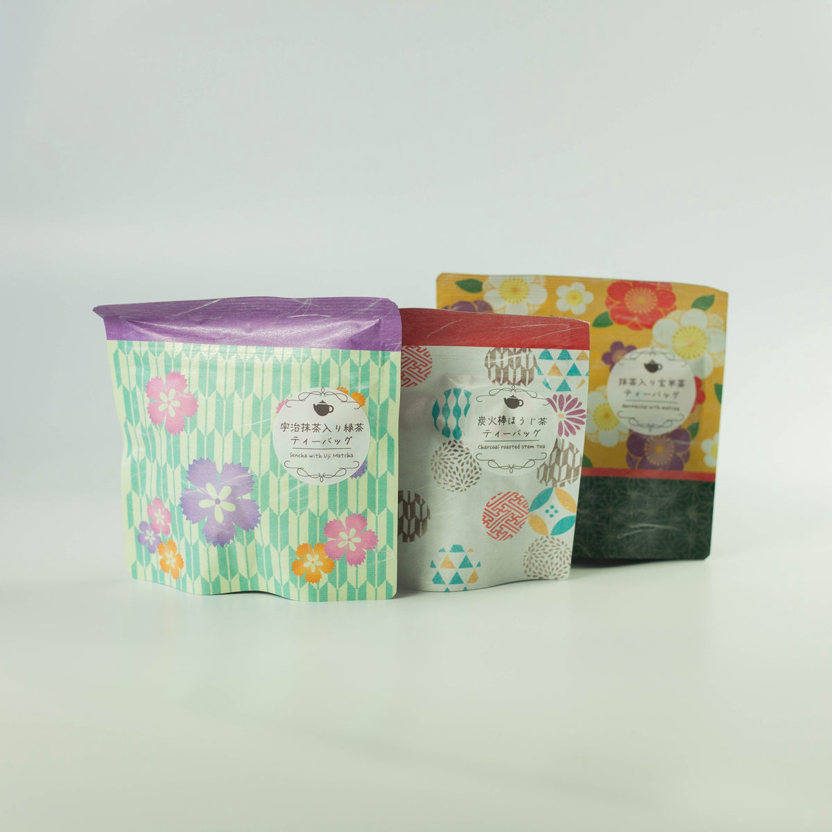 Three Chikiriya tea pouches from the Wafu Green Tea Gift Set – green floral Uji Matcha Green Tea, white geometric Charcoal Roasted Hojicha, and yellow floral Genmaicha with Matcha, standing upright on white background