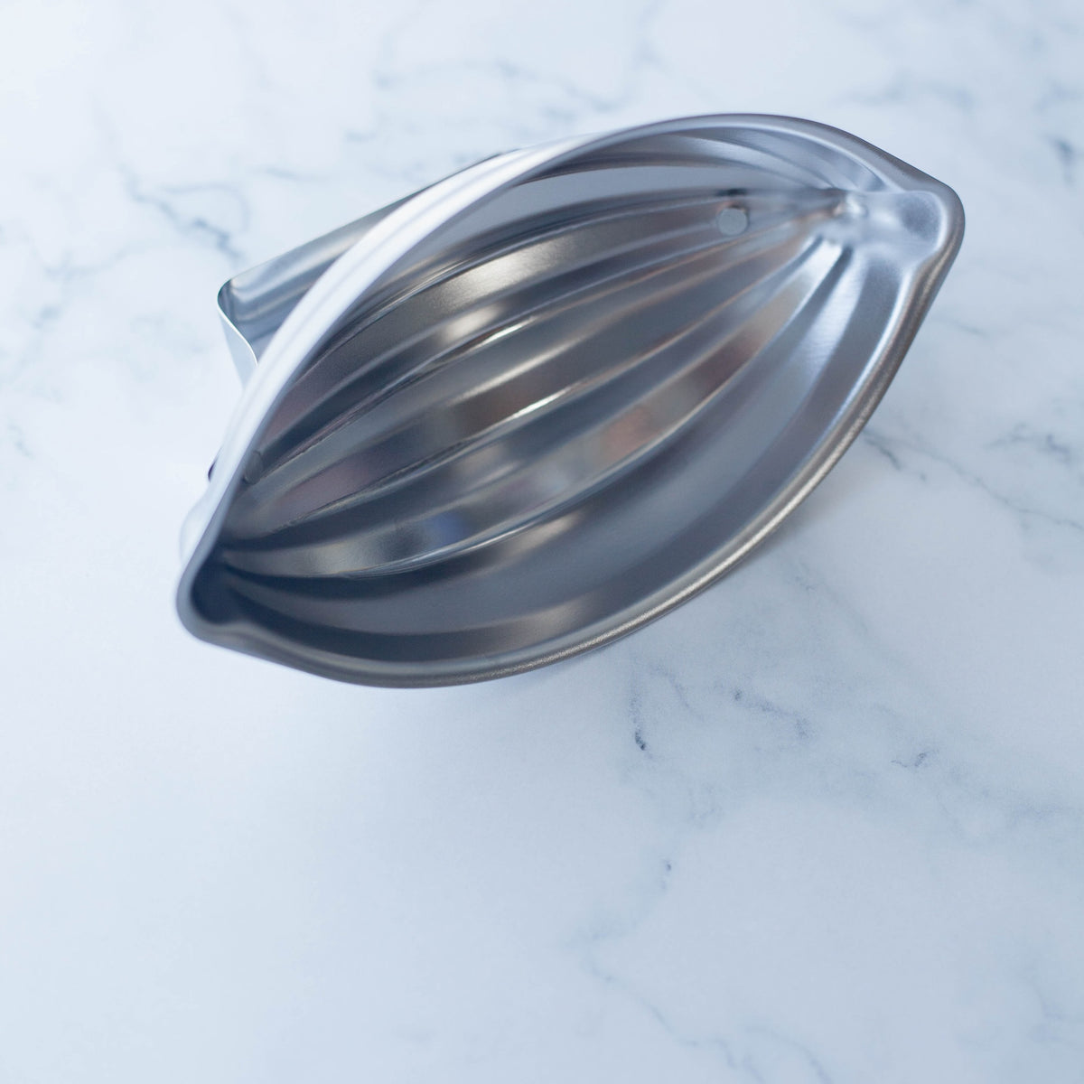 Restaurant Style Rice Mold open – stainless steel interior showing ribbed oval cavity, angled view on marble surface