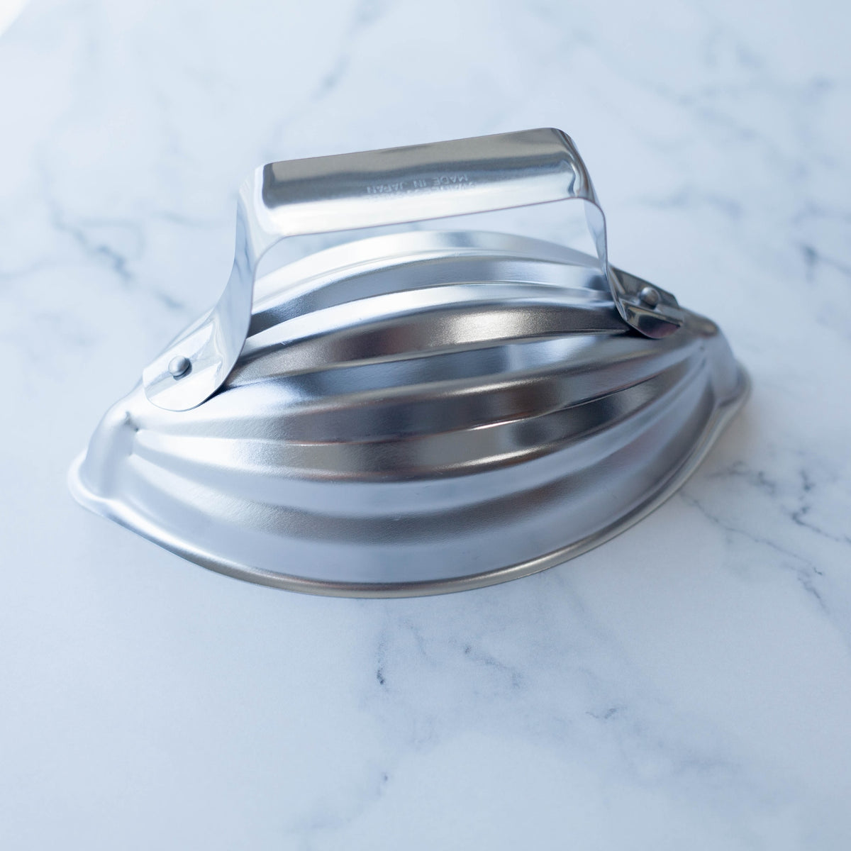 Restaurant Style Rice Mold – stainless steel oval mold closed with handle, angled top view on marble surface