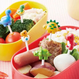 Set of 6 colorful dinosaur bento picks including red T-rex, green triceratops, yellow stegosaurus, blue brontosaurus, orange baby T-rex hatching from egg, and green baby dinosaur