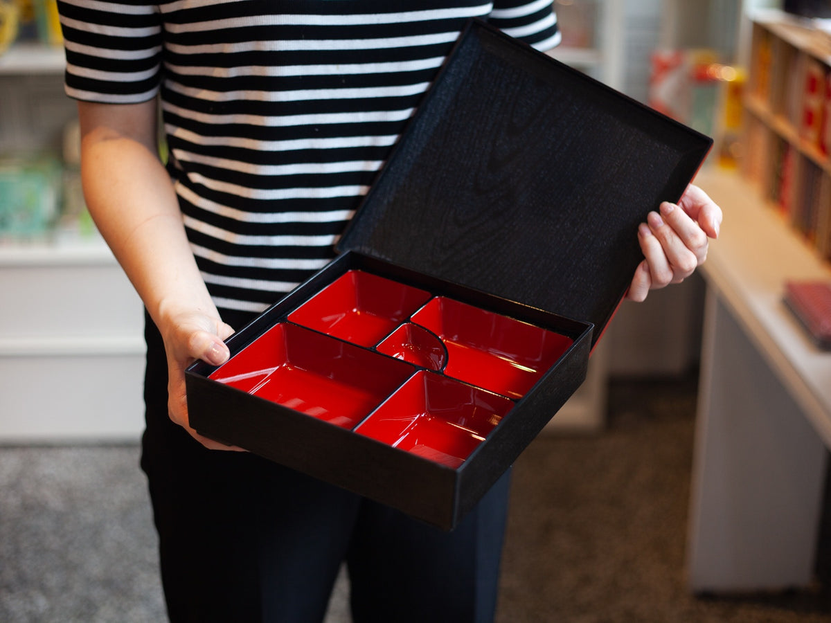 Japanese lacquerware-style bento box with black wood-grain textured lid and dark red base, elegant square lunch box, made in Japan