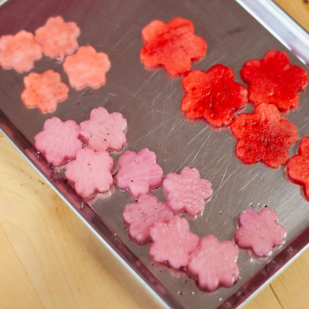 Sakura Cutter Set in use – pink and red sakura-shaped jelly pieces cut and arranged on stainless steel tray